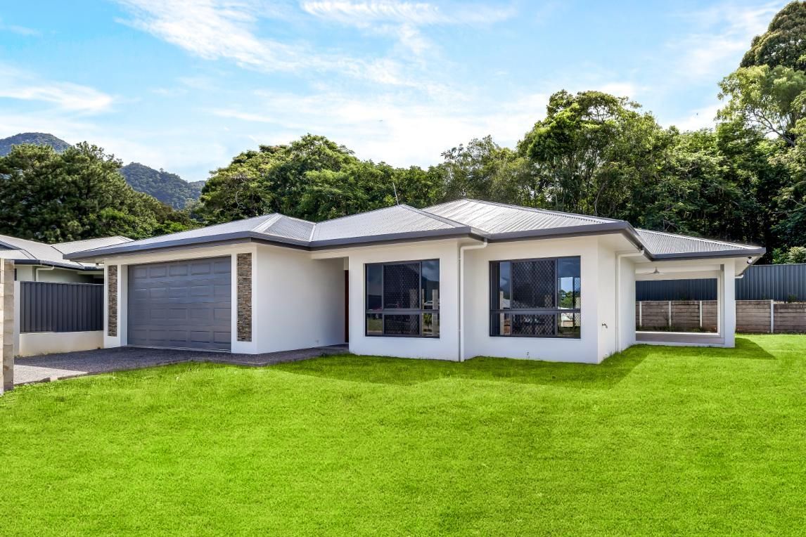 A White House With a Lot of Windows is Sitting on Top of a Lush Green Lawn — Ashlee Jones Homes in Gordonvale, QLD