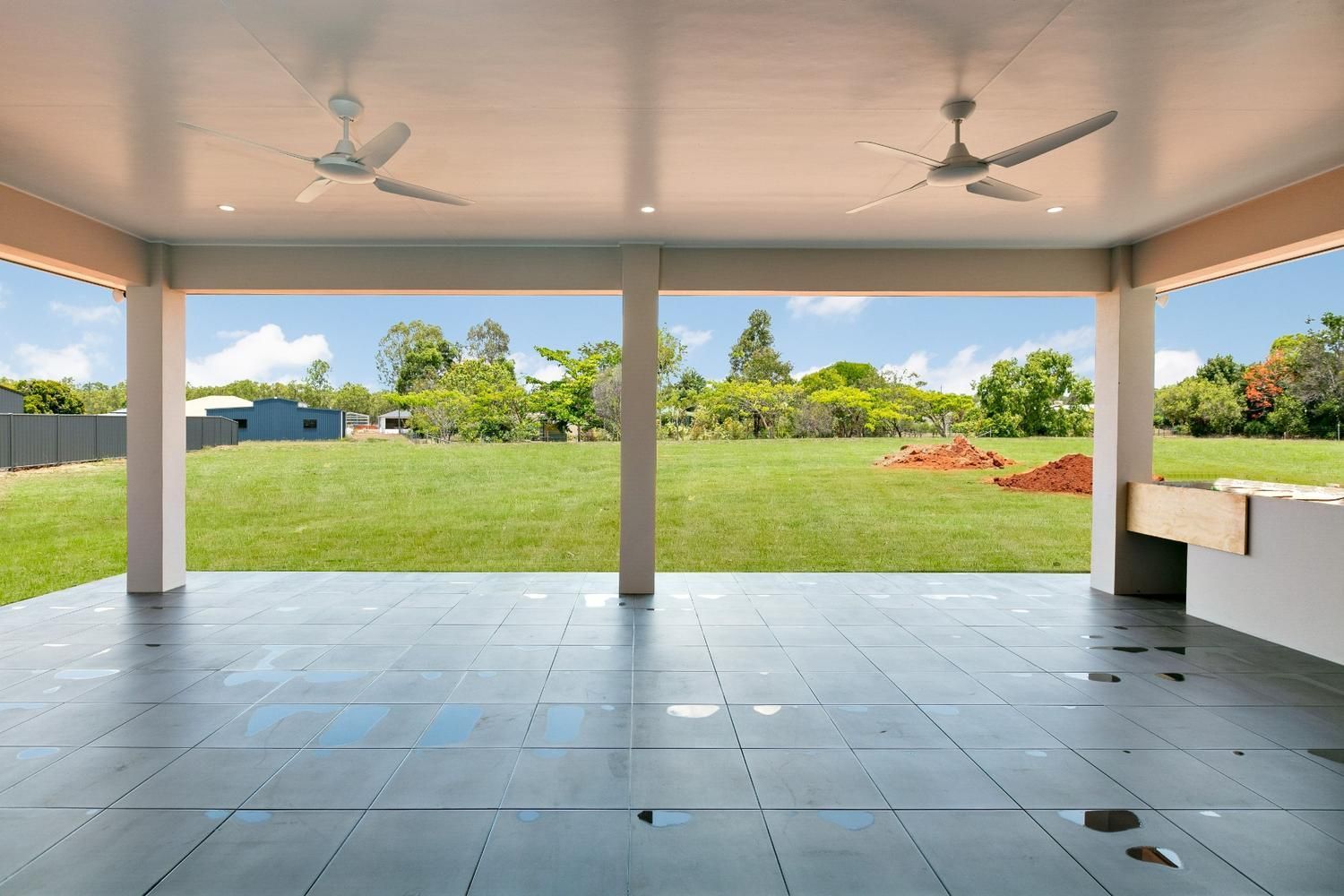 An Empty Patio With a Ceiling Fan and a View of a Grassy Field — Ashlee Jones Homes in Gordonvale, QLD