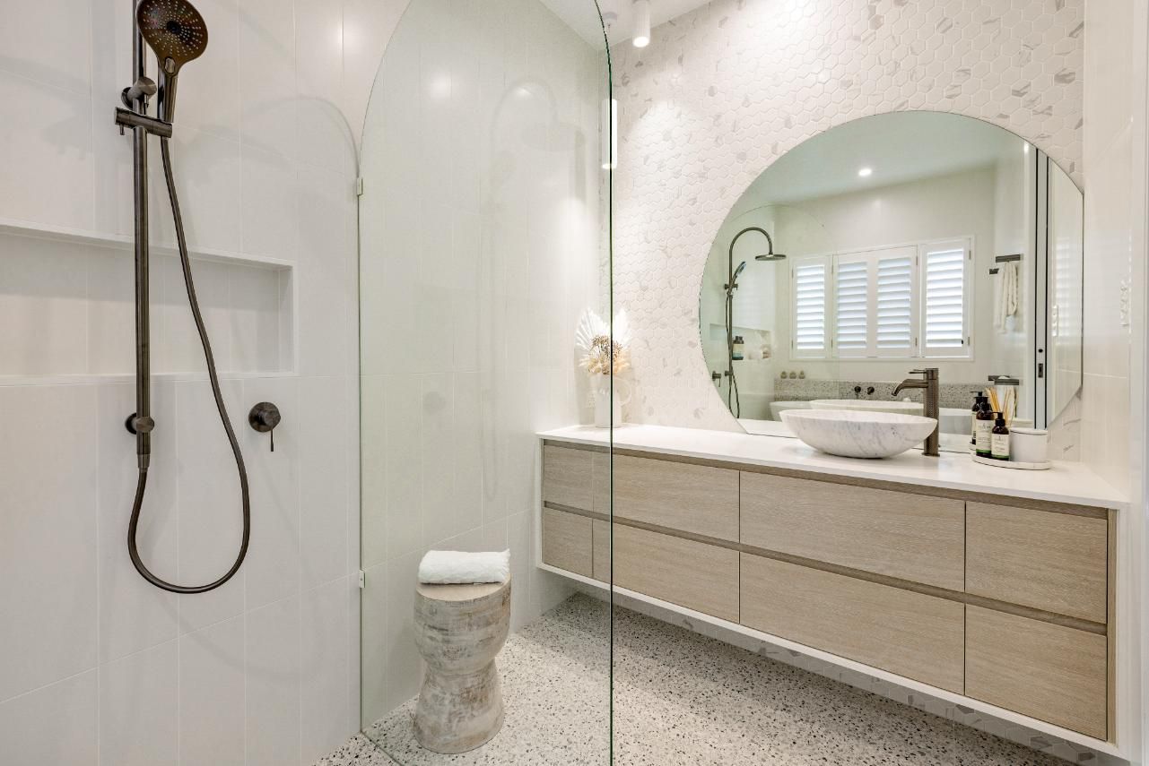 A Bathroom With a Toilet, Sink, Shower and Mirror — Ashlee Jones Homes in Gordonvale, QLD
