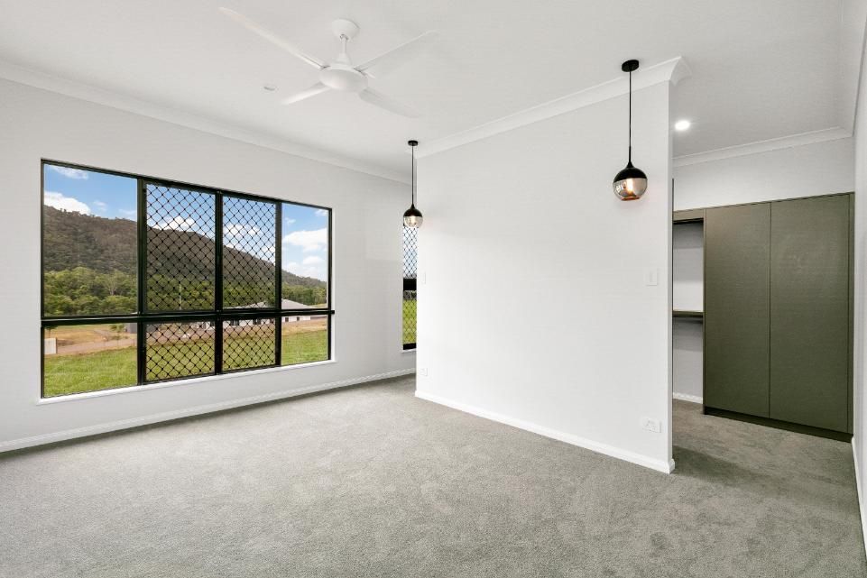 An Empty Living Room With a Ceiling Fan and a Large Window — Ashlee Jones Homes in Gordonvale, QLD