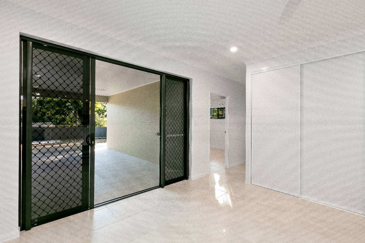 An Empty Room With a Sliding Glass Door Leading to a Patio — Ashlee Jones Homes in Gordonvale, QLD
