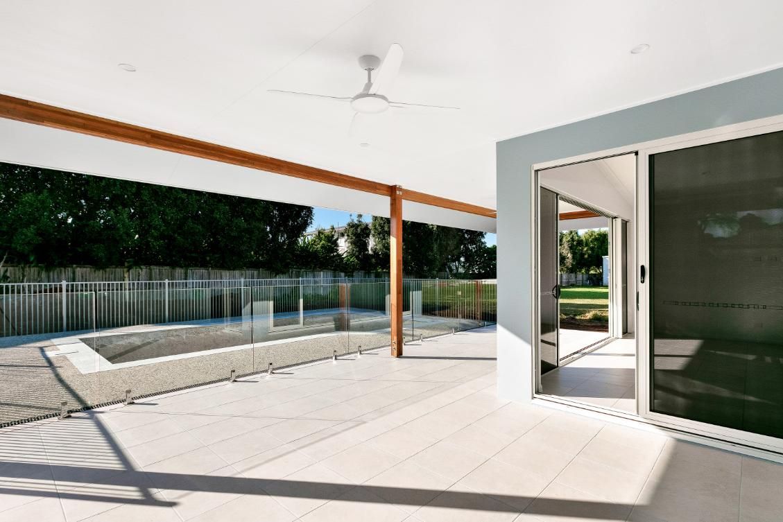 A Large Patio With Sliding Glass Doors and a Ceiling Fan — Ashlee Jones Homes in Gordonvale, QLD