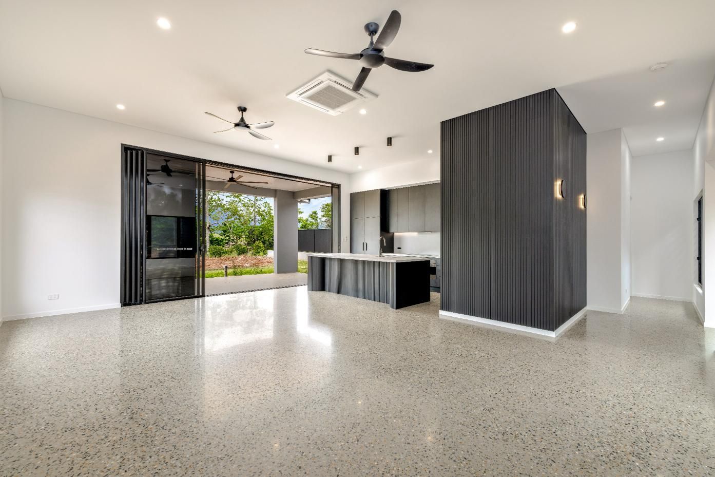 A Large Empty Room with A Ceiling Fan and A Kitchen — Ashlee Jones Homes in Gordonvale, QLD
