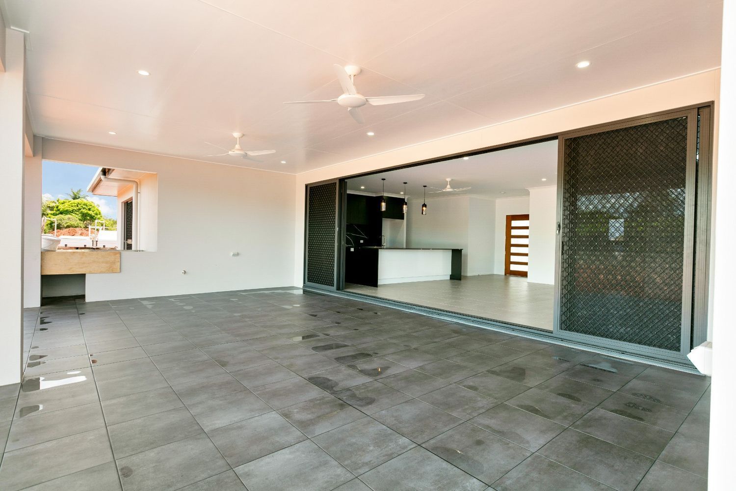 A Large Empty Room With Sliding Glass Doors and a Ceiling Fan — Ashlee Jones Homes in Gordonvale, QLD