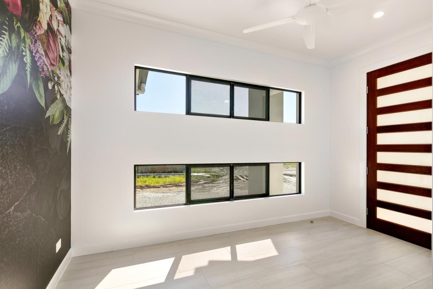 An Empty Room With Two Windows and a Ceiling Fan — Ashlee Jones Homes in Gordonvale, QLD