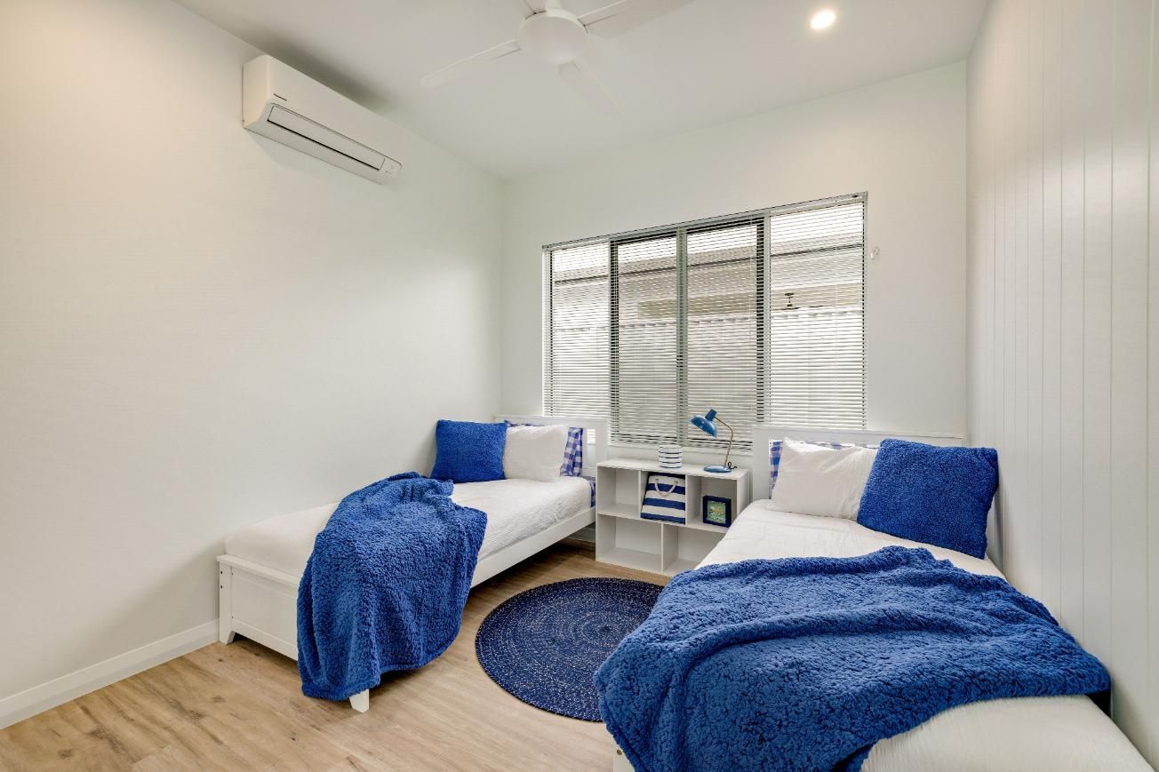 A Bedroom With Two Beds and a Ceiling Fan — Ashlee Jones Homes in Gordonvale, QLD