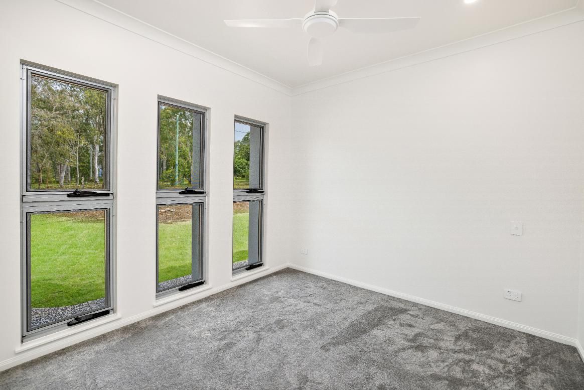 An Empty Bedroom With a Ceiling Fan and Three Windows — Ashlee Jones Homes in Gordonvale, QLD