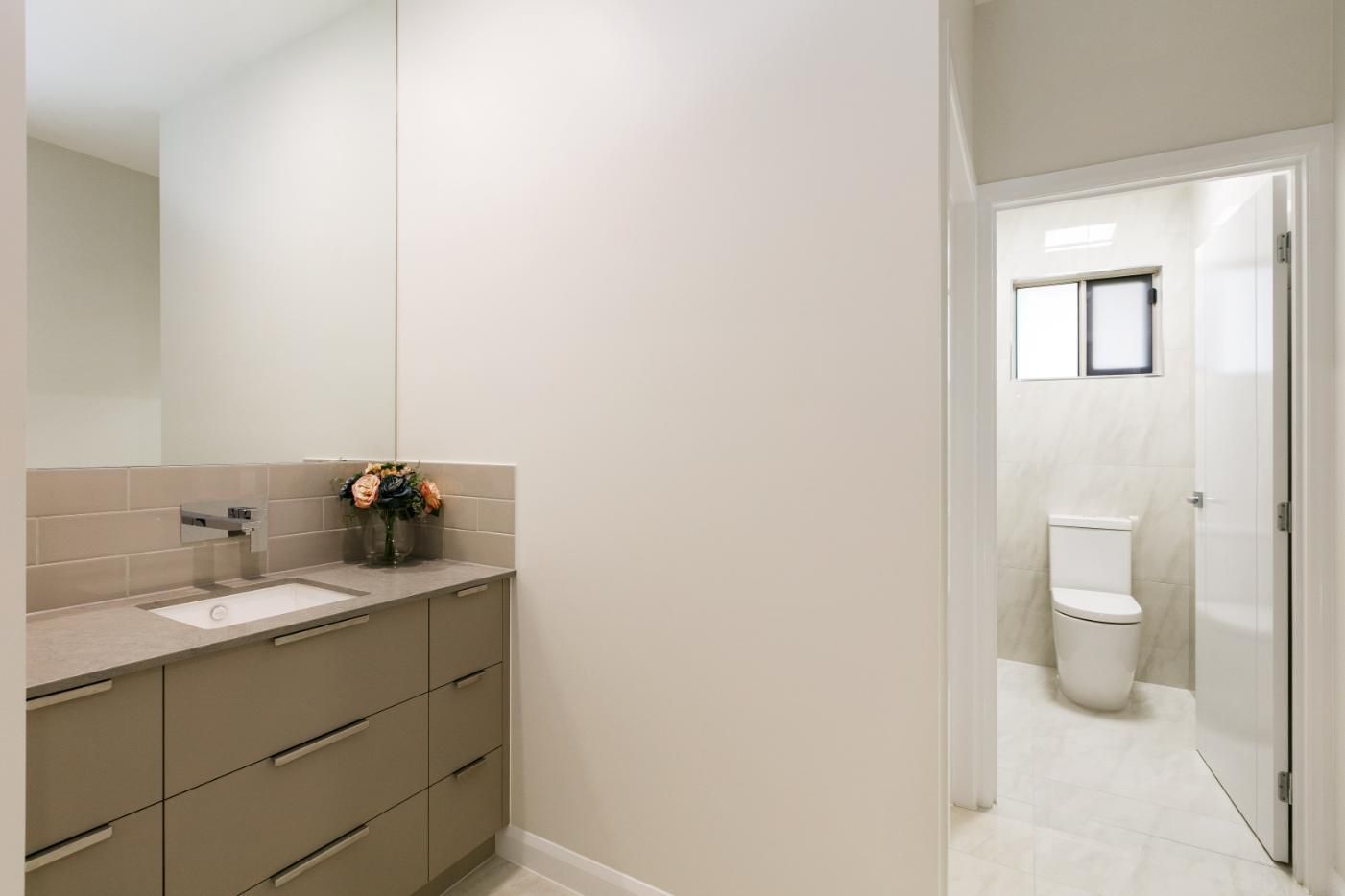 A Bathroom With a Sink, Toilet and Mirror — Ashlee Jones Homes in Gordonvale, QLD