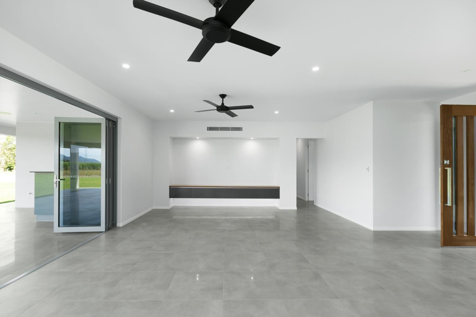 An Empty Room With a Ceiling Fan and a Door — Ashlee Jones Homes in Gordonvale, QLD