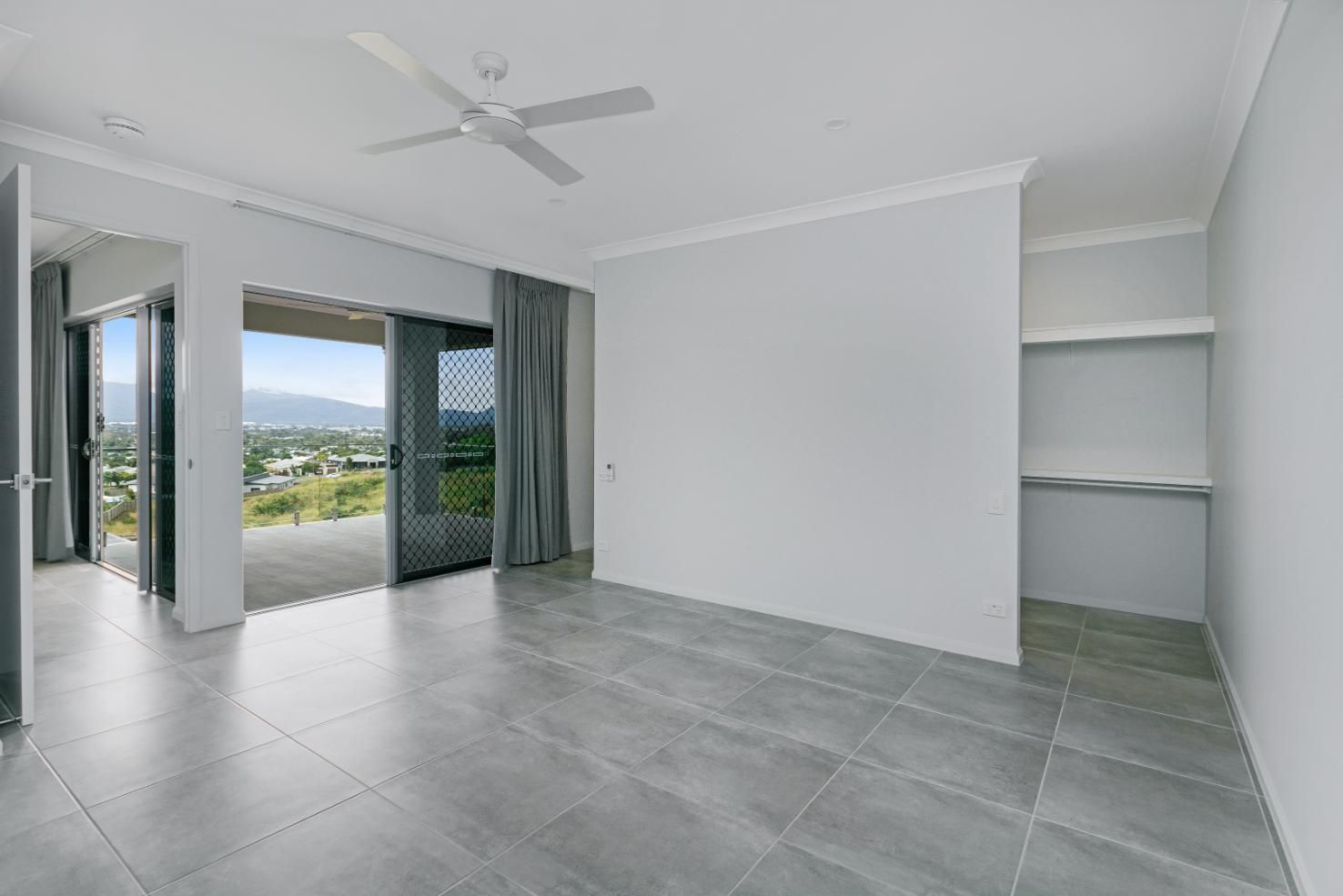 An Empty Living Room With a Ceiling Fan and Sliding Glass Doors — Ashlee Jones Homes in Gordonvale, QLD