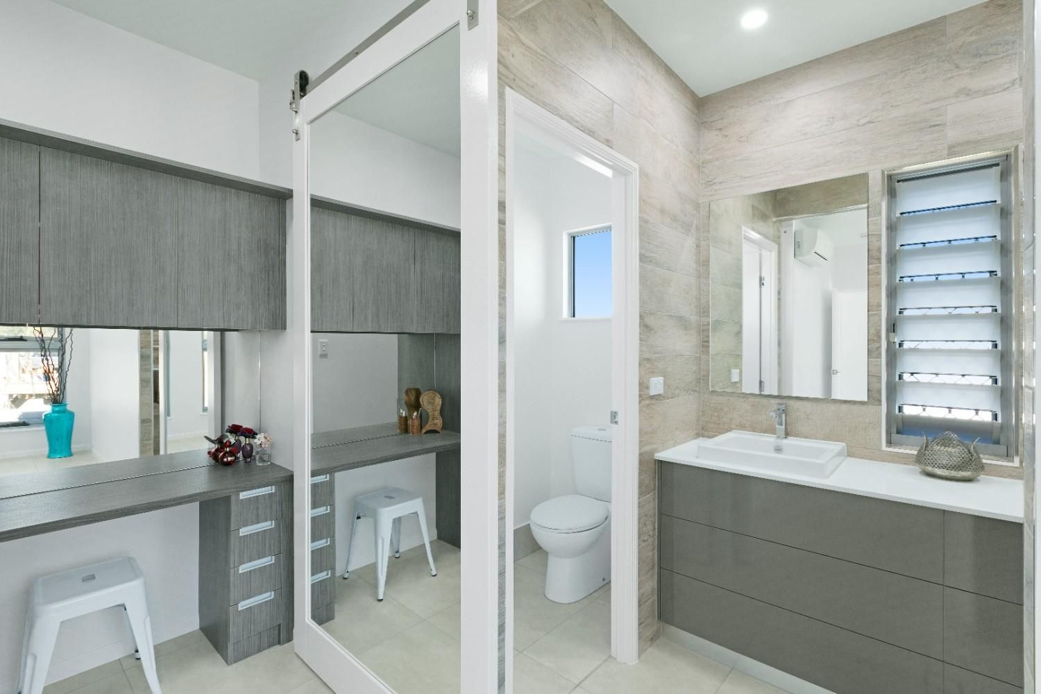 A Bathroom With a Sink, Toilet and Mirrors — Ashlee Jones Homes in Gordonvale, QLD