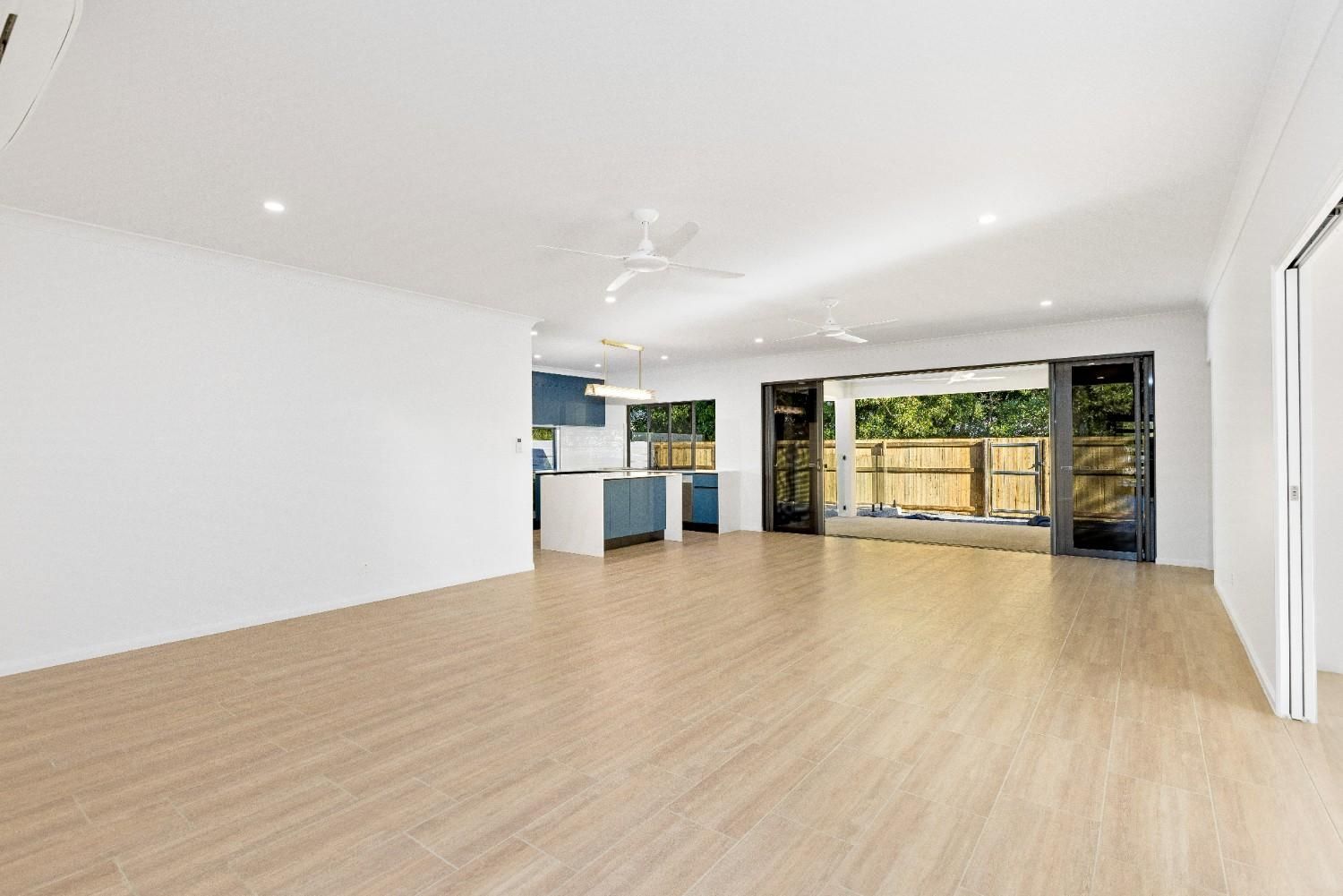 An Empty Living Room With Hardwood Floors and a Ceiling Fan — Ashlee Jones Homes in Gordonvale, QLD