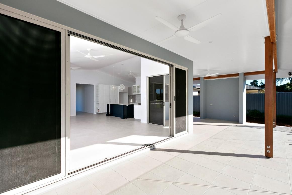 A Large Sliding Glass Door is Open to a Patio With a Ceiling Fan — Ashlee Jones Homes in Gordonvale, QLD