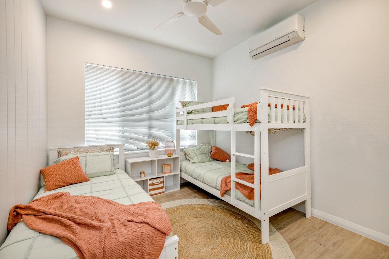 A Bedroom With Two Bunk Beds and a Ceiling Fan — Ashlee Jones Homes in Gordonvale, QLD