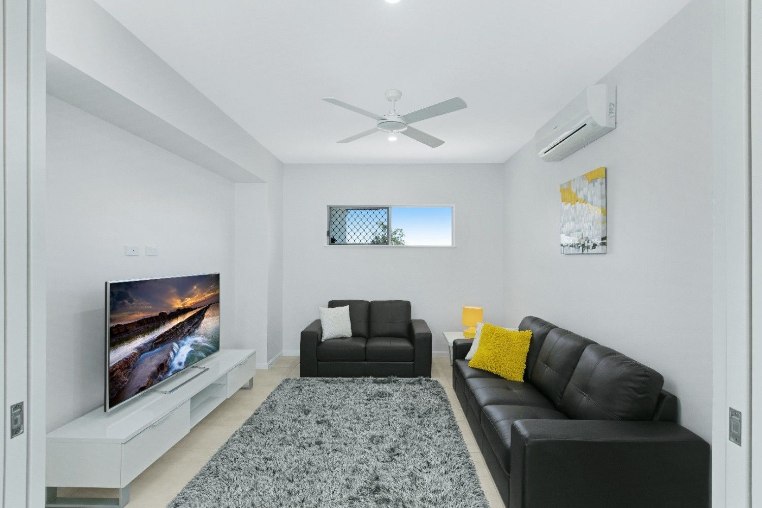 A Living Room With a Black Couch and a Flat Screen Tv — Ashlee Jones Homes in Gordonvale, QLD