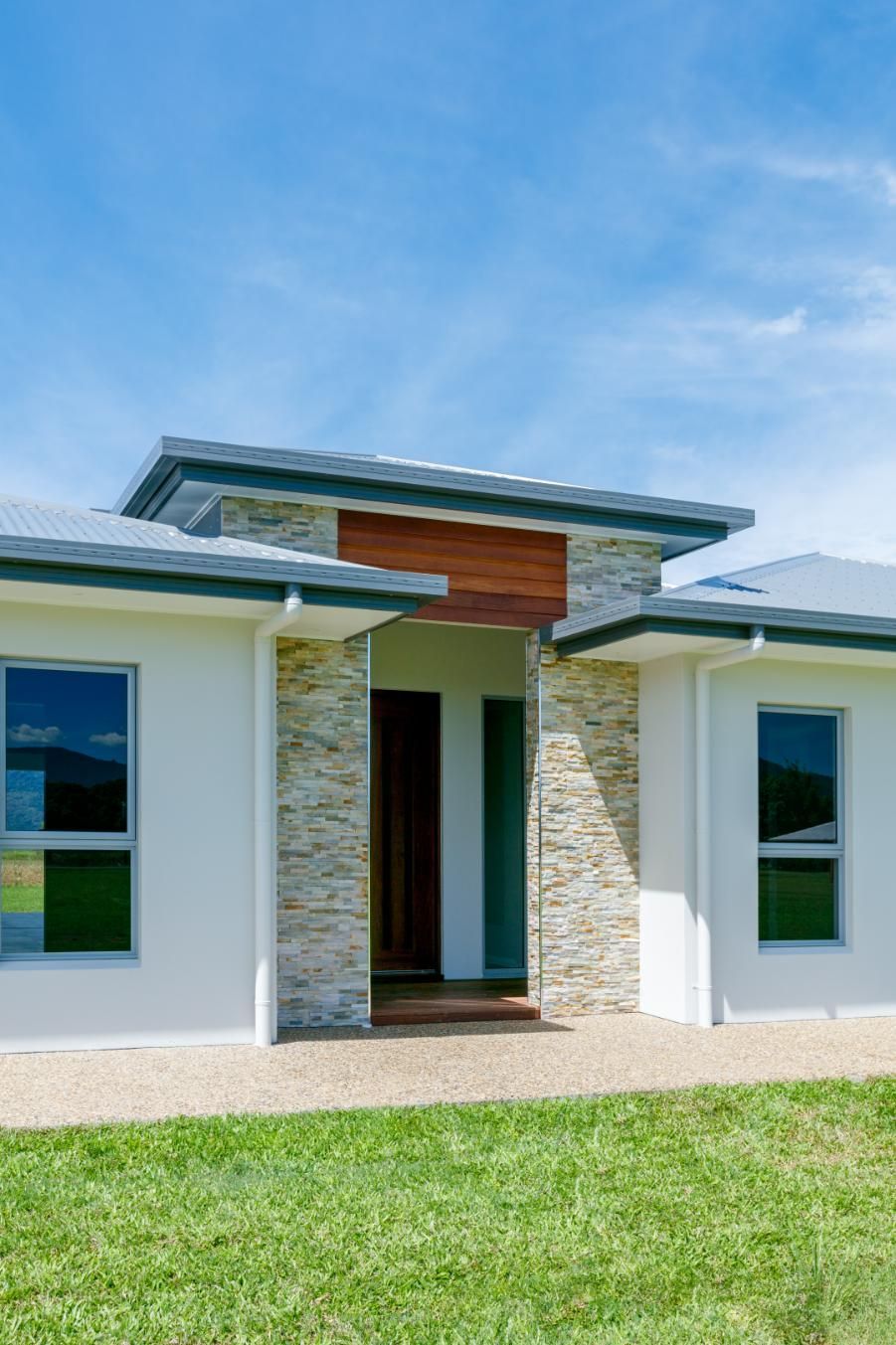 A White House With a Stone Facade is Sitting on Top of a Lush Green Lawn — Ashlee Jones Homes in Gordonvale, QLD