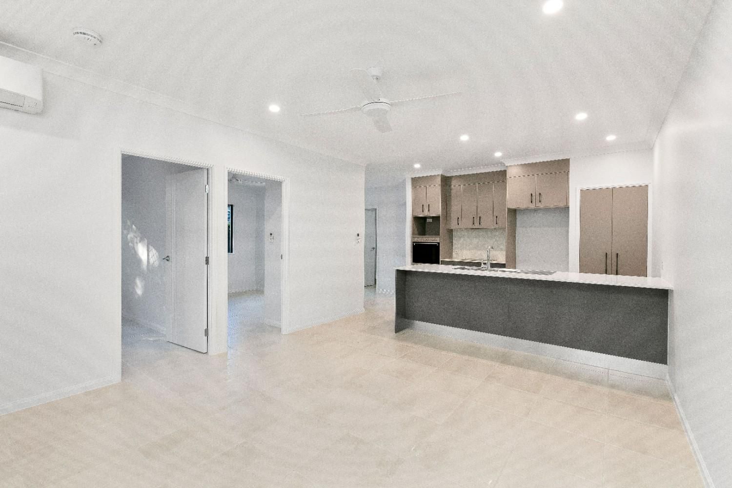 An Empty Living Room With a Kitchen and a Ceiling Fan — Ashlee Jones Homes in Gordonvale, QLD