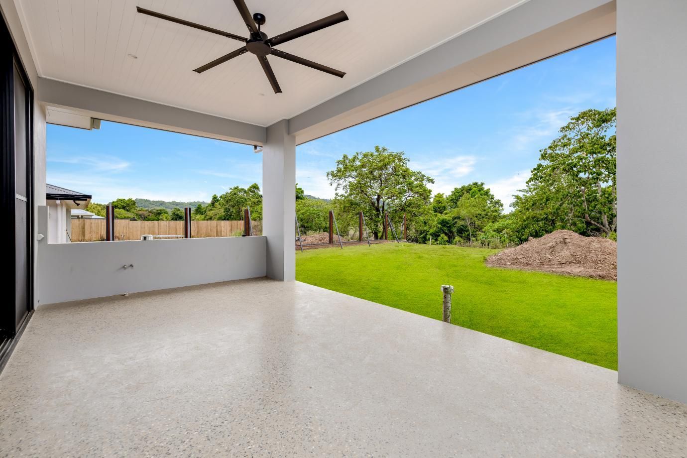 An Empty Patio with A Ceiling Fan and A View of A Grassy Field — Ashlee Jones Homes in Gordonvale, QLD