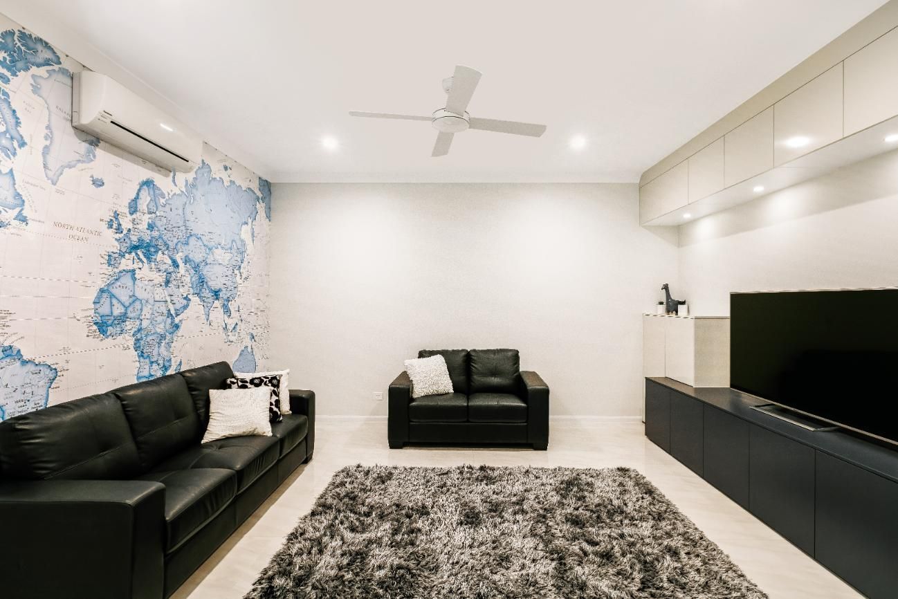 A Living Room With a Couch, Rug, Television and Ceiling Fan — Ashlee Jones Homes in Gordonvale, QLD