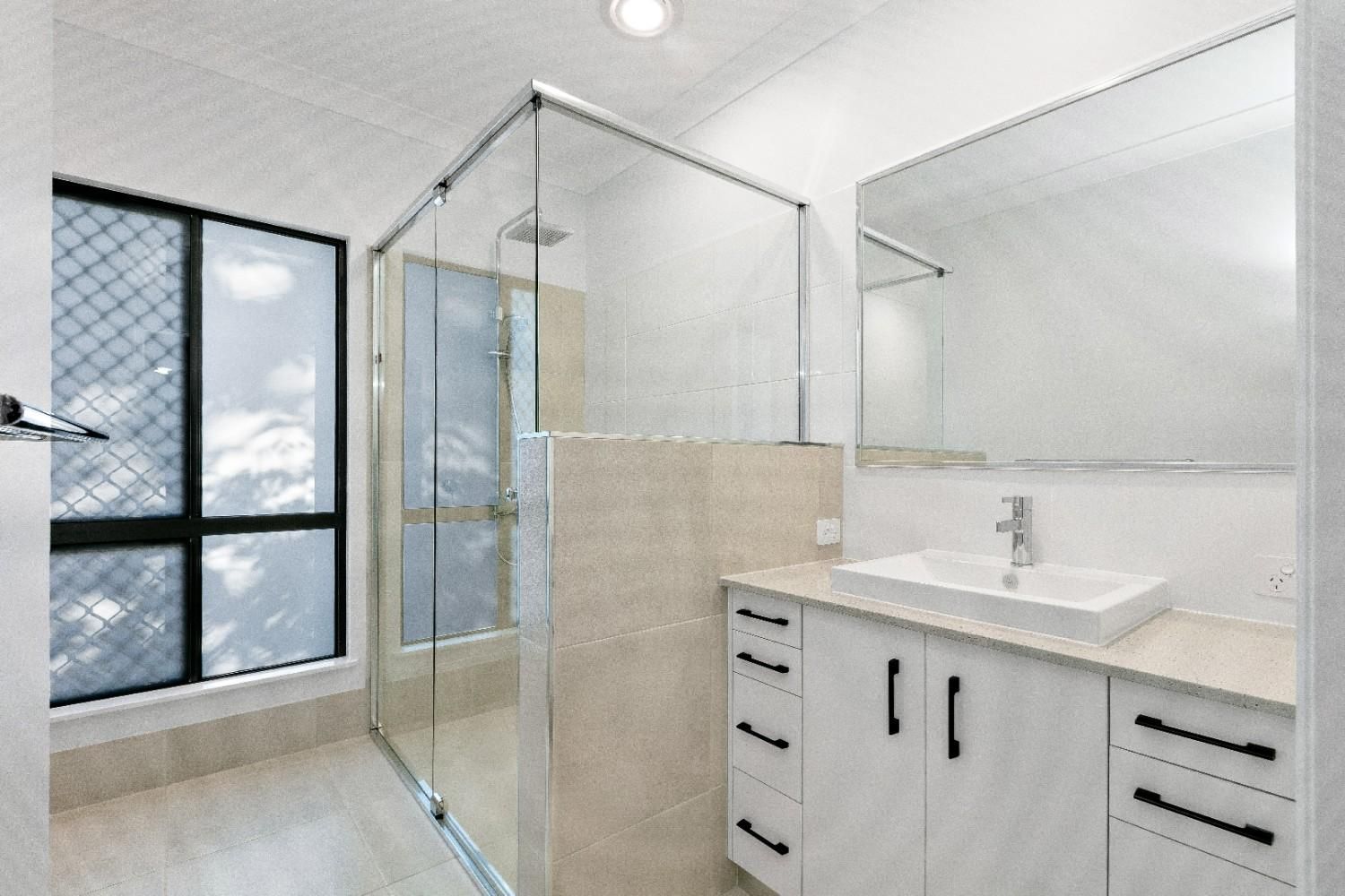 A Bathroom With a Sink, Mirror and Shower — Ashlee Jones Homes in Gordonvale, QLD