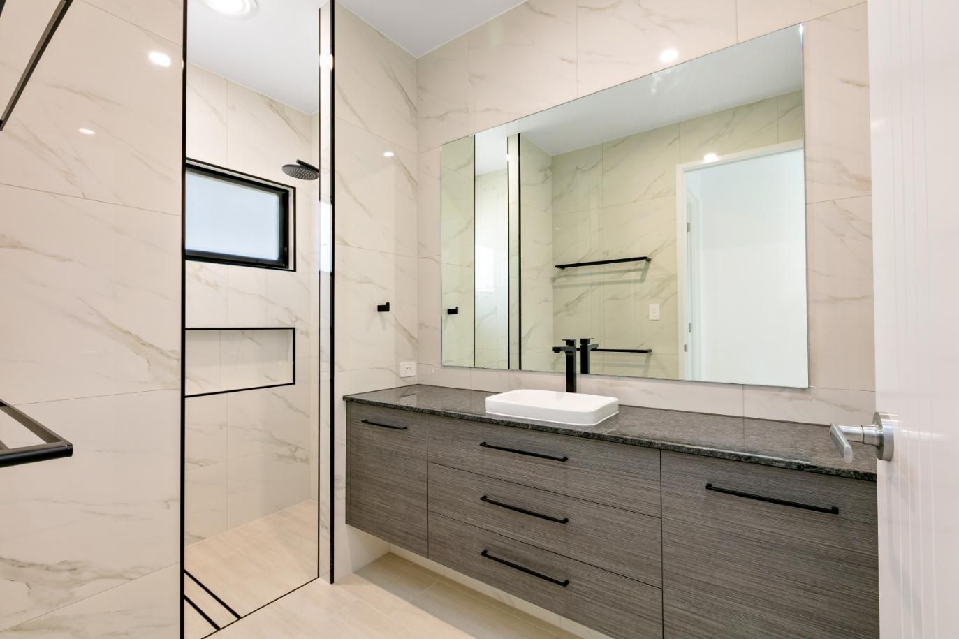 A Bathroom With a Sink, Mirror and Walk in Shower — Ashlee Jones Homes in Gordonvale, QLD