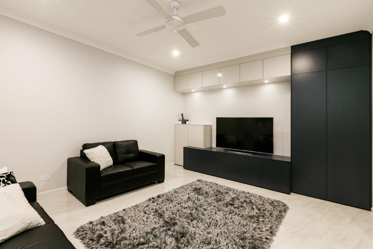 A Living Room With a Couch, Rug, Television and Ceiling Fan — Ashlee Jones Homes in Gordonvale, QLD
