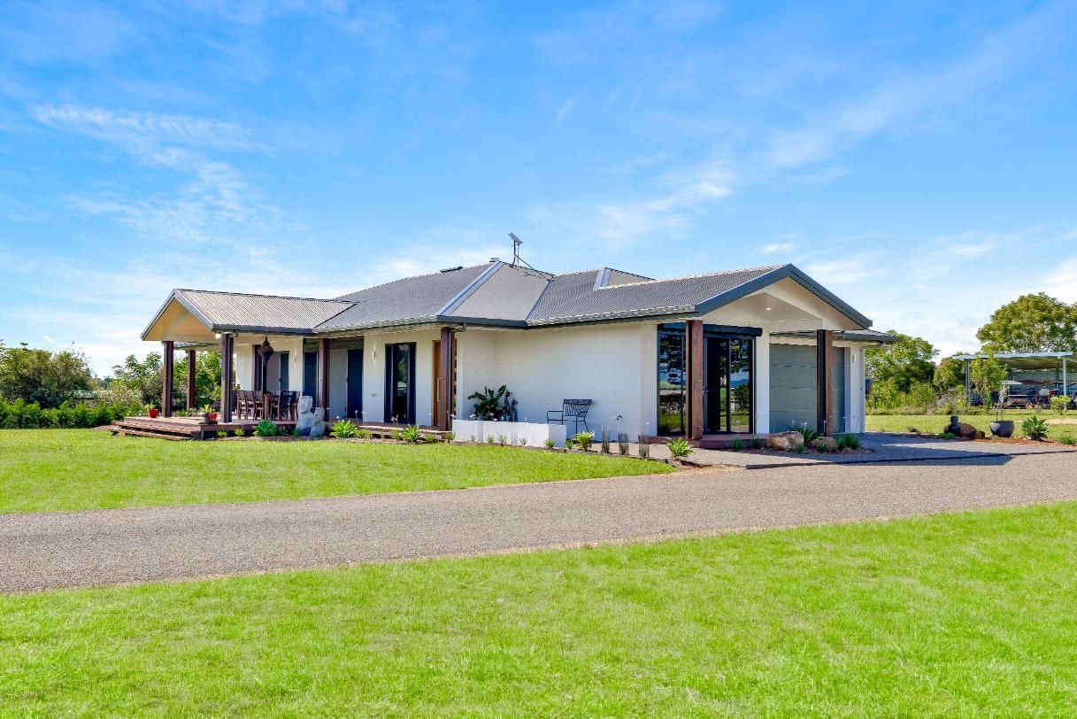 A Large White House is Sitting on Top of a Lush Green Field — Ashlee Jones Homes in Gordonvale, QLD