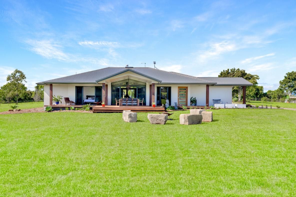 A Large White House is Sitting on Top of a Lush Green Field — Ashlee Jones Homes in Gordonvale, QLD