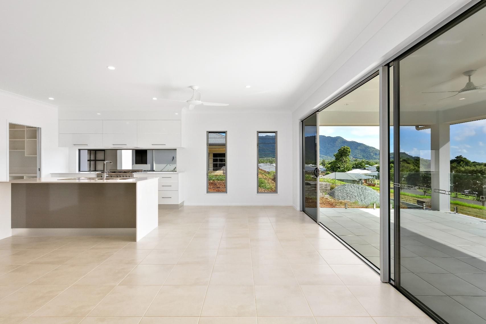 A Large Empty Room With a Kitchen and Sliding Glass Doors — Ashlee Jones Homes in Gordonvale, QLD