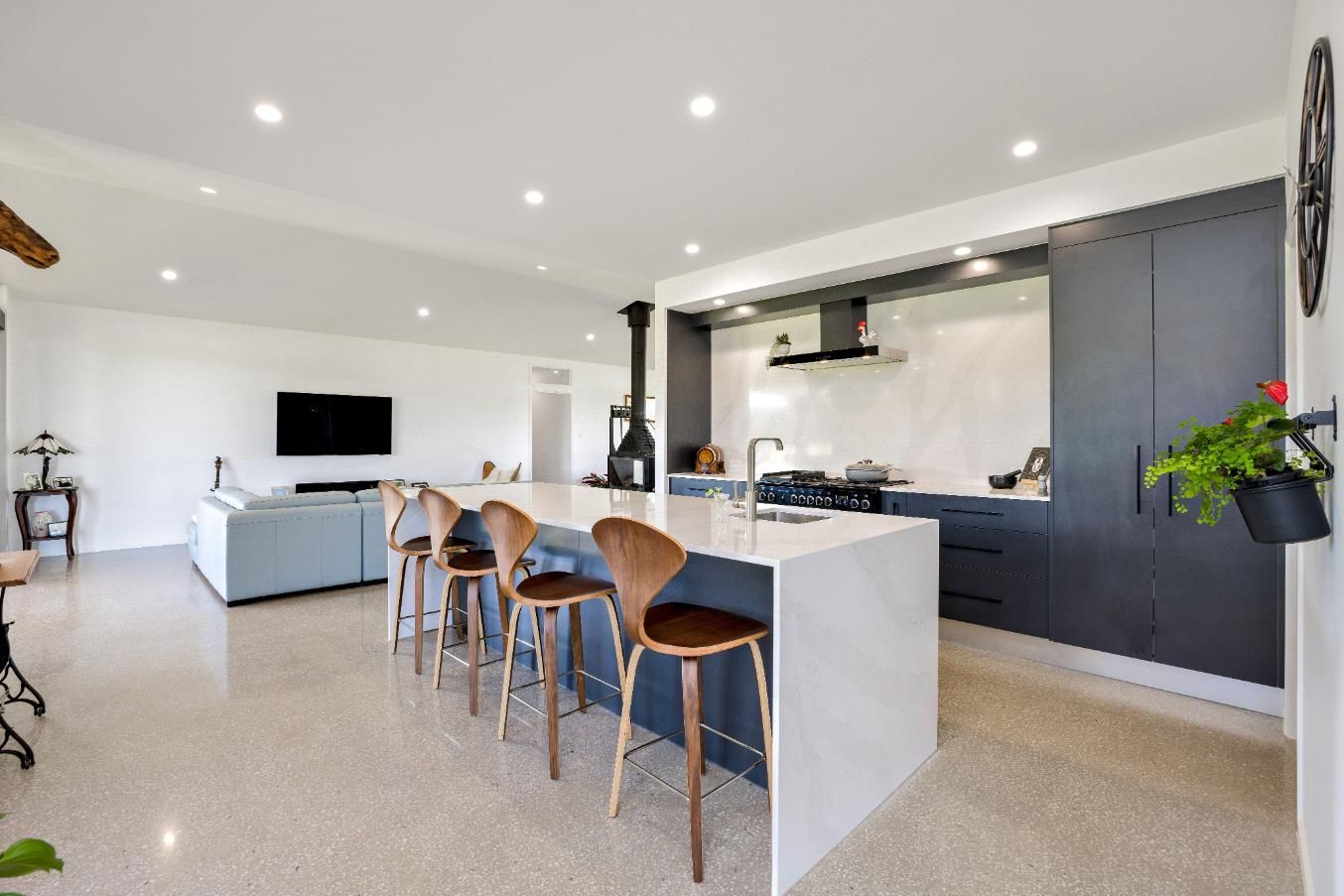 A Kitchen With a Large Island and Stools in a House — Ashlee Jones Homes in Gordonvale, QLD