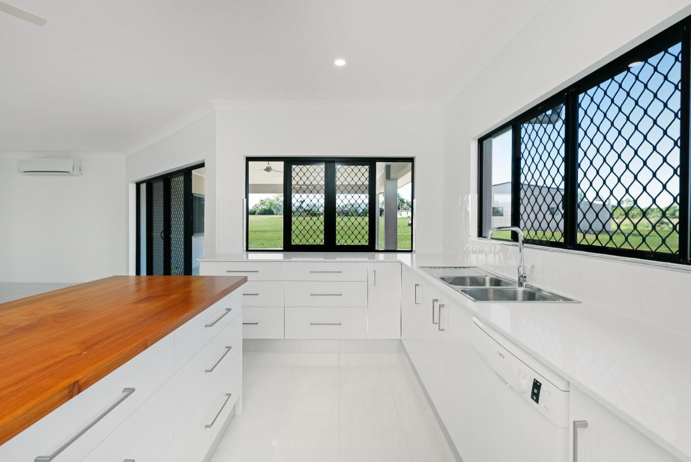 An Empty Kitchen With White Cabinets and a Wooden Countertop — Ashlee Jones Homes in Gordonvale, QLD