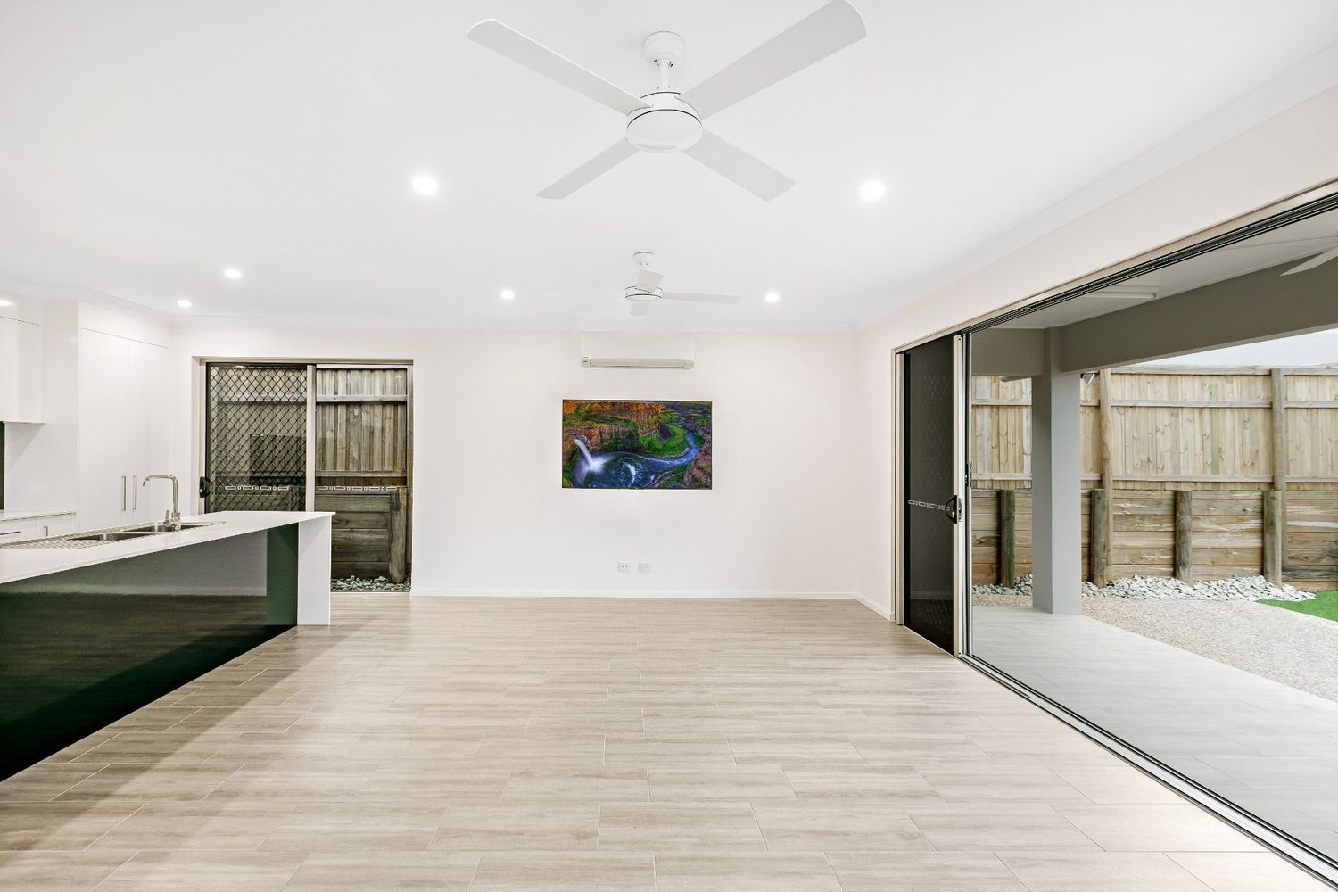 A Living Room With a Ceiling Fan and a Painting on the Wall — Ashlee Jones Homes in Gordonvale, QLD
