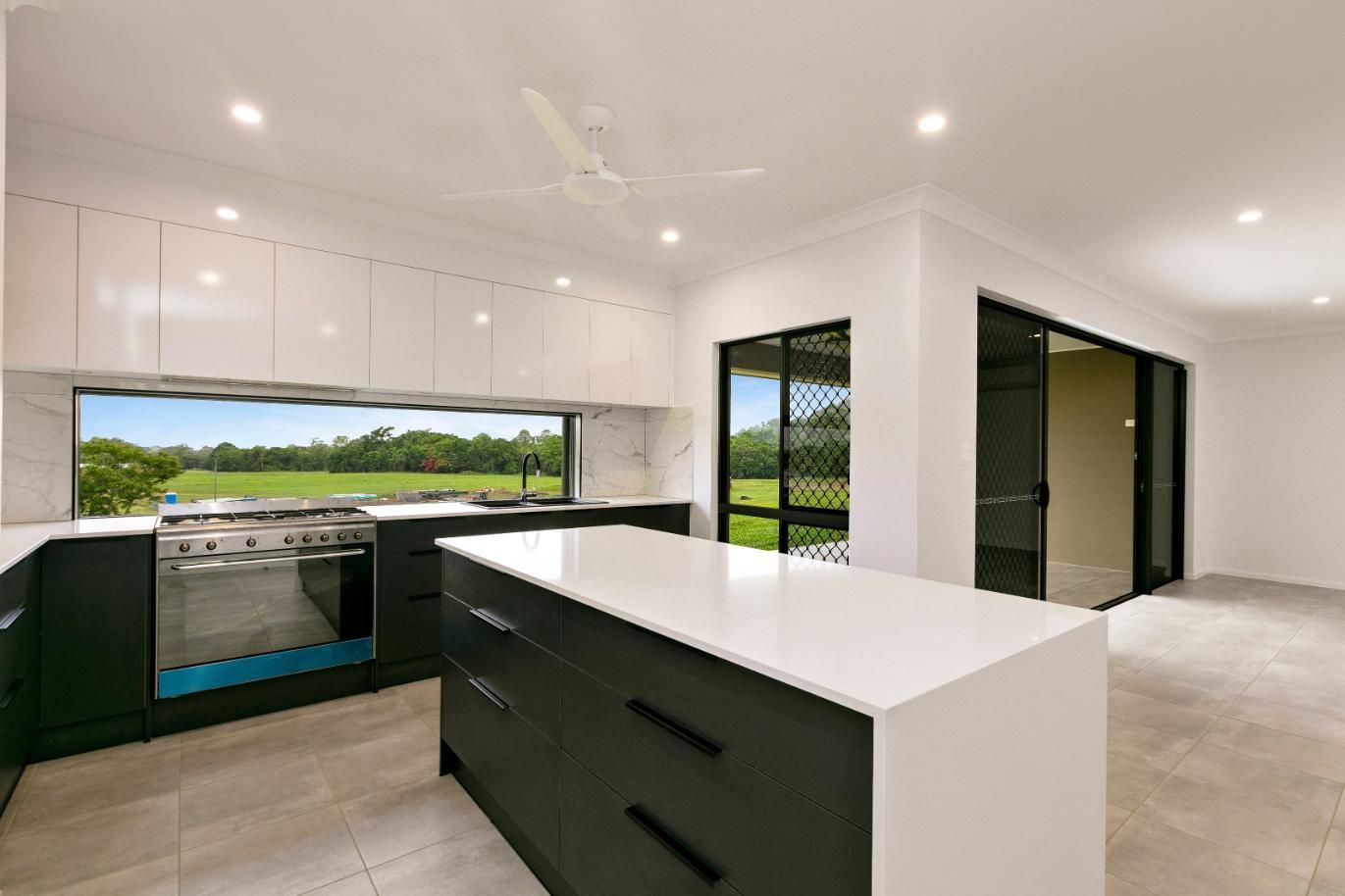 A Kitchen With Black Cabinets and White Counter Tops and a Large Island — Ashlee Jones Homes in Gordonvale, QLD