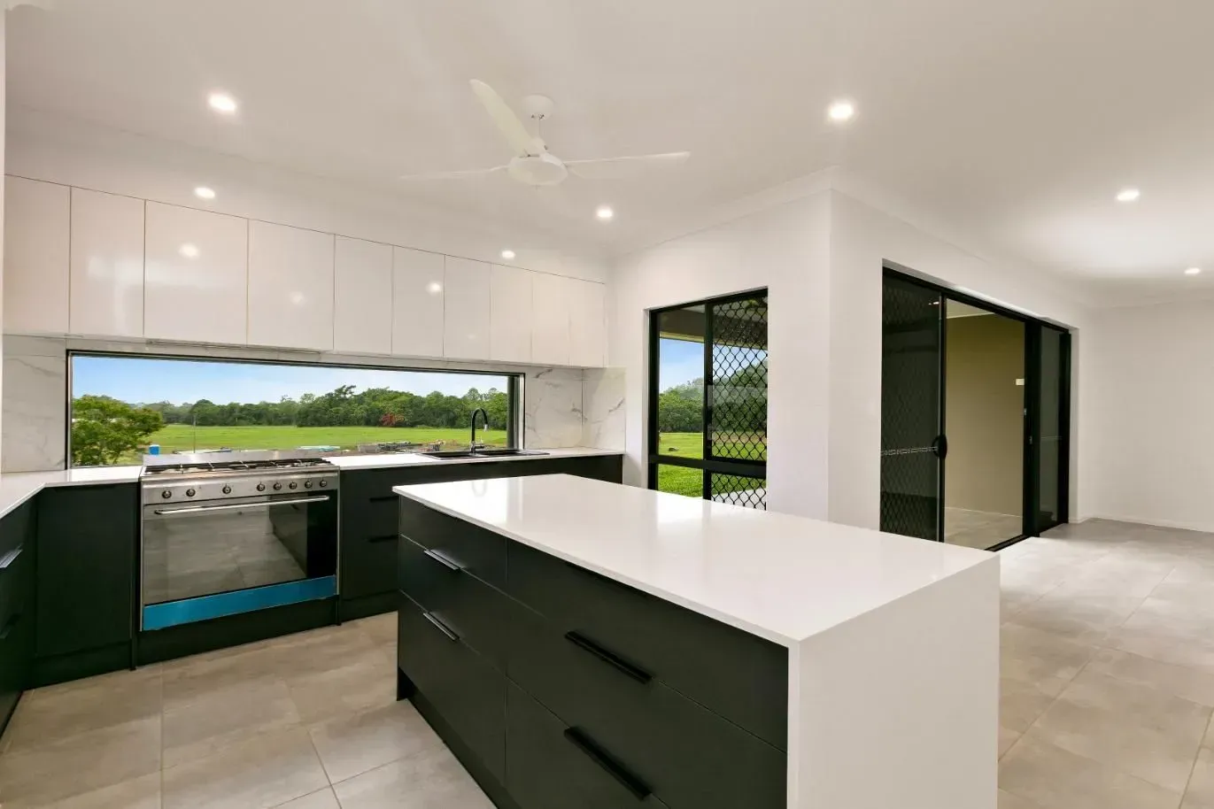 An Empty Room With Hardwood Floors and a Ceiling Fan — Ashlee Jones Homes in Gordonvale, QLD