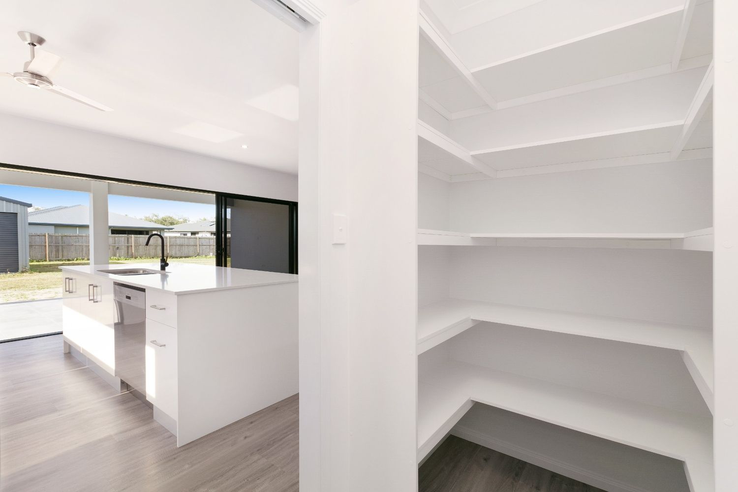 A Kitchen With a Large Island and a Pantry With Shelves — Ashlee Jones Homes in Gordonvale, QLD