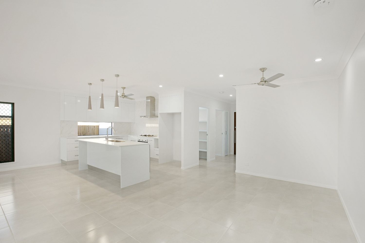 An Empty Room With a Kitchen and a Ceiling Fan — Ashlee Jones Homes in Gordonvale, QLD