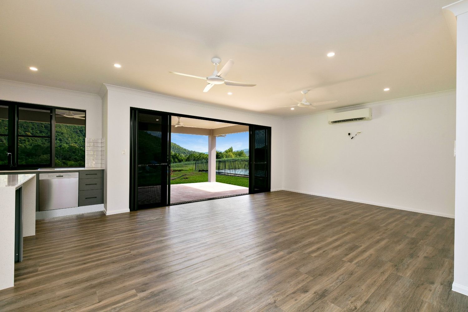 An Empty Living House With Hardwood Floors and a Ceiling Fan — Ashlee Jones Homes in Gordonvale, QLD