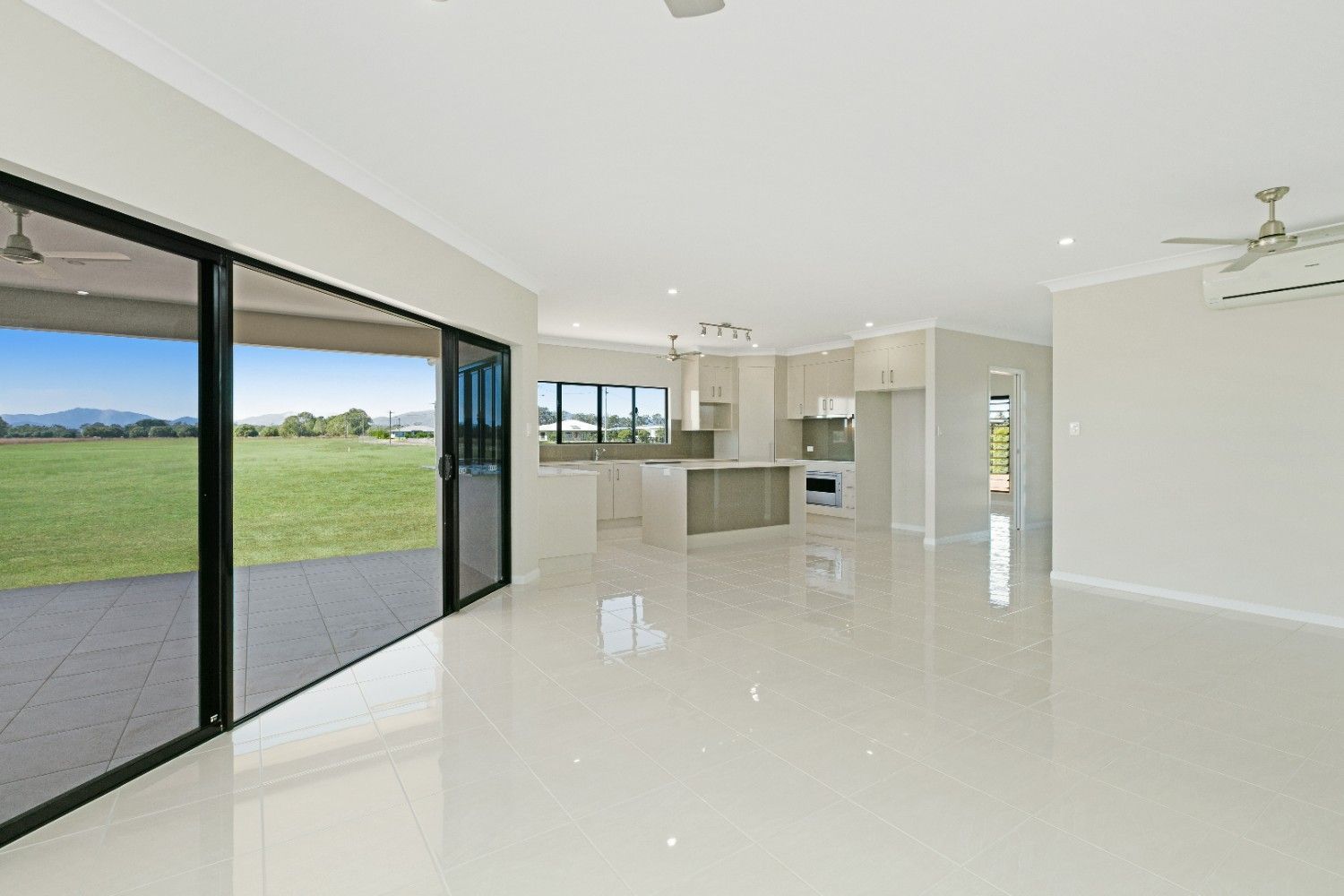 A Large Empty Room With Sliding Glass Doors and a Ceiling Fan — Ashlee Jones Homes in Gordonvale, QLD