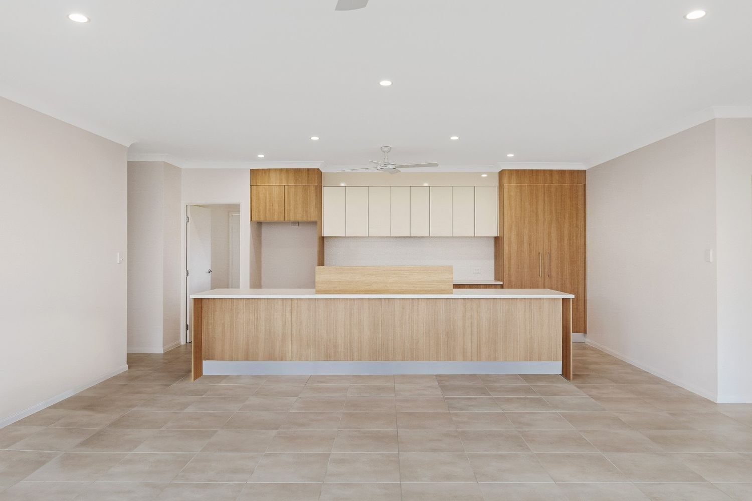 An Empty Kitchen With Wooden Cabinets and a Large Island — Ashlee Jones Homes in Gordonvale, QLD