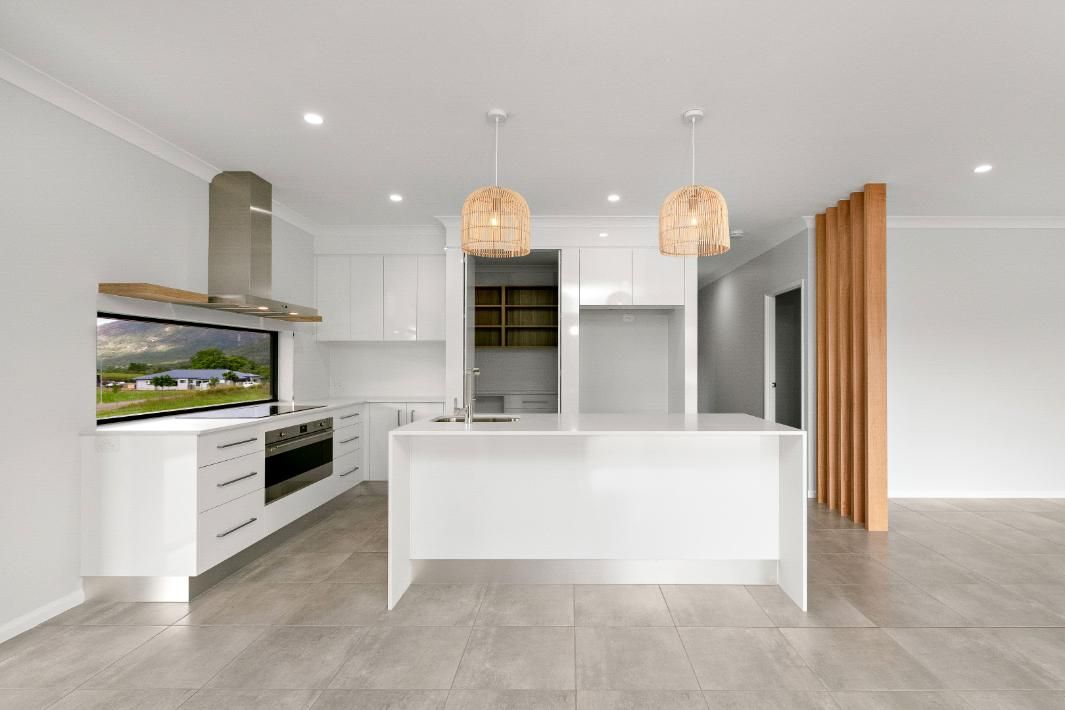 A Kitchen With White Cabinets, Stainless Steel Appliances, and a Large Island — Ashlee Jones Homes in Gordonvale, QLD