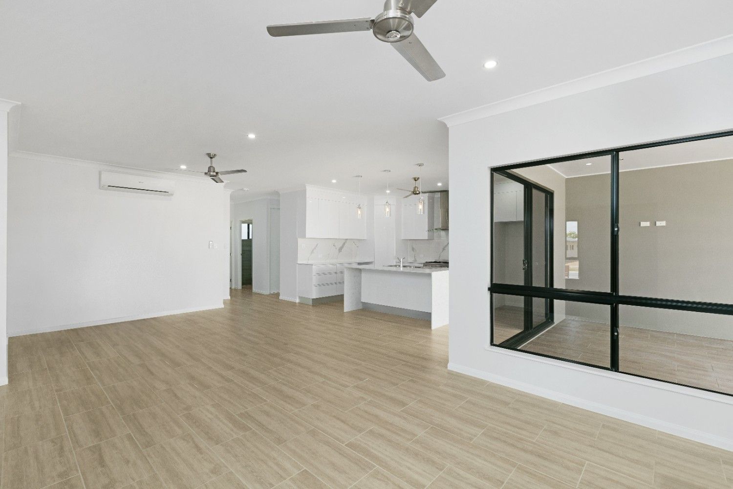 An Empty Living Room With Hardwood Floors and a Ceiling Fan — Ashlee Jones Homes in Gordonvale, QLD