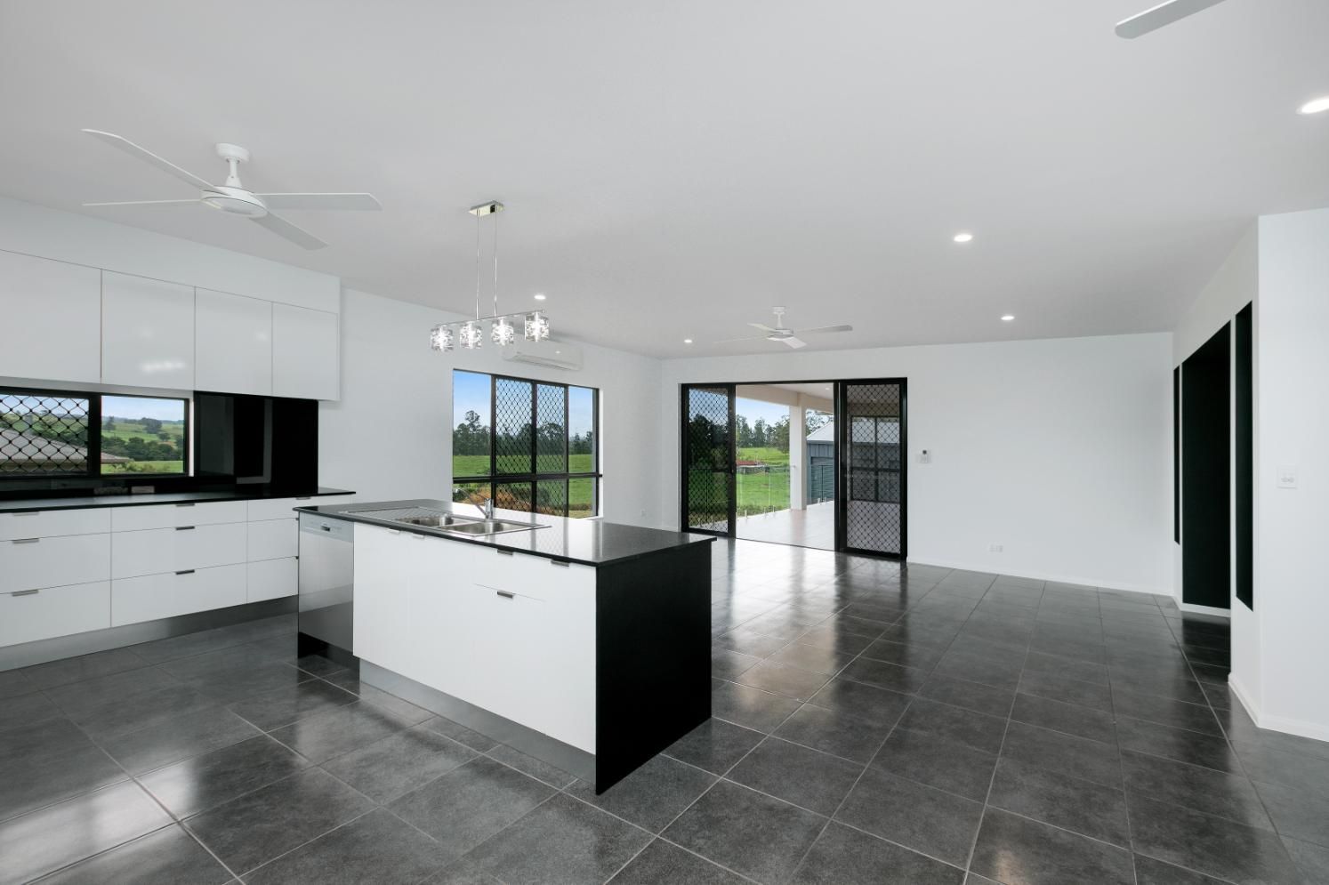 An Empty Kitchen With White Cabinets and a Black Island — Ashlee Jones Homes in Gordonvale, QLD