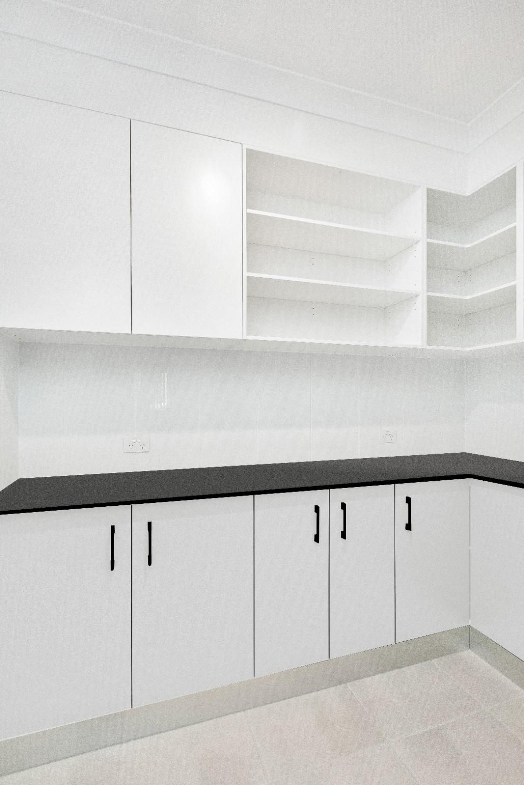 A Kitchen With White Cabinets and Black Counter Tops — Ashlee Jones Homes in Gordonvale, QLD