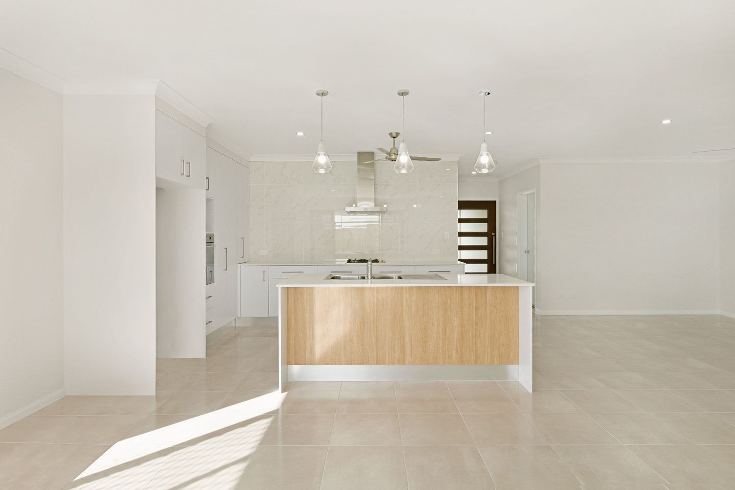 An Empty Kitchen With White Cabinets and a Wooden Island — Ashlee Jones Homes in Gordonvale, QLD