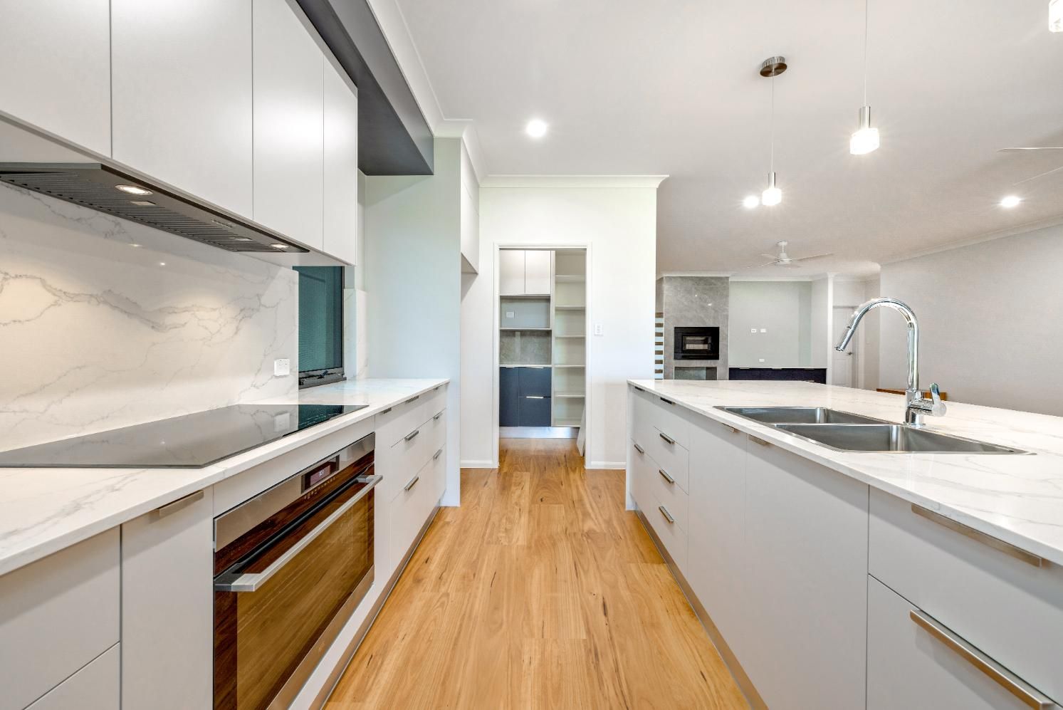 A Kitchen With White Cabinets, a Sink, and a Stove Top Oven — Ashlee Jones Homes in Gordonvale, QLD