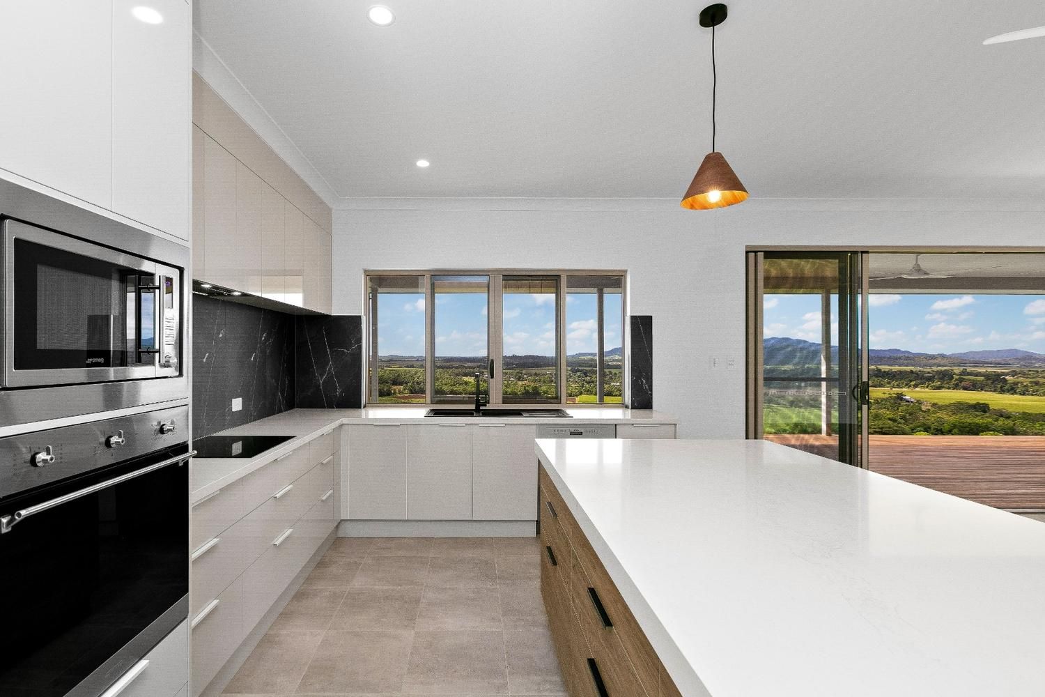 A Kitchen With White Cabinets, Stainless Steel Appliances, and a Large Island — Ashlee Jones Homes in Gordonvale, QLD