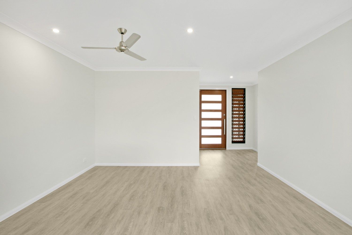 An Empty Room With a Ceiling Fan and a Door — Ashlee Jones Homes in Gordonvale, QLD