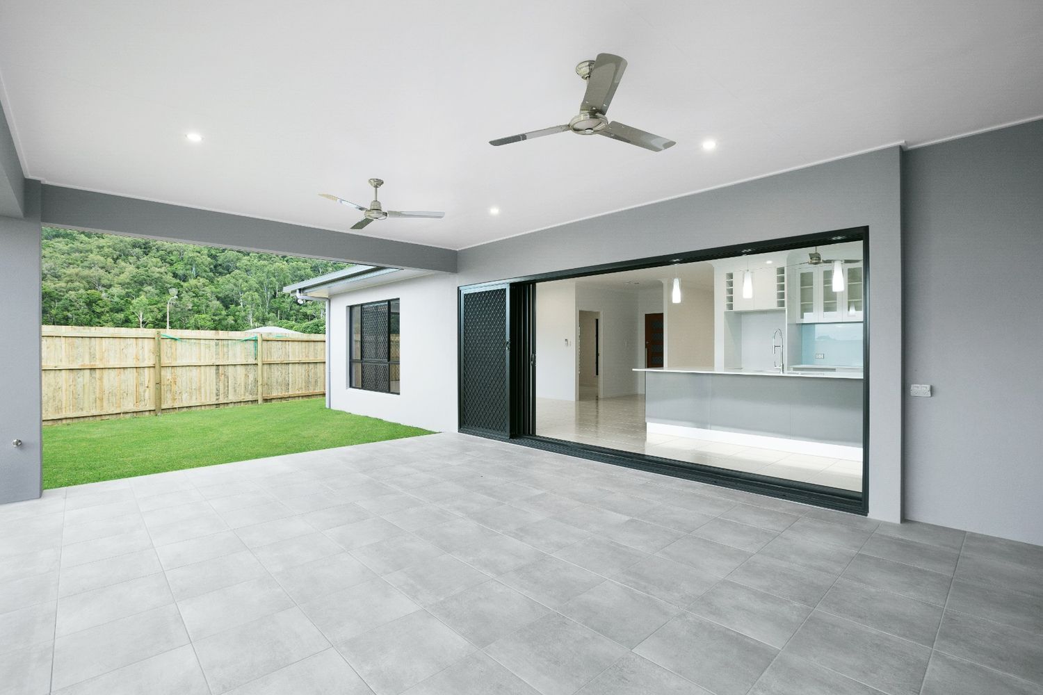 An Empty House With a Large Sliding Glass Door and a Ceiling Fan — Ashlee Jones Homes in Gordonvale, QLD