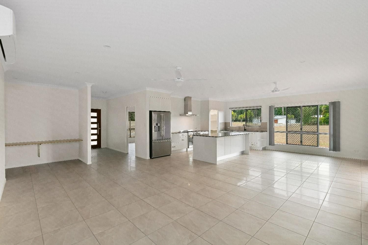 A Large Empty Room With a Kitchen and a Refrigerator — Ashlee Jones Homes in Gordonvale, QLD