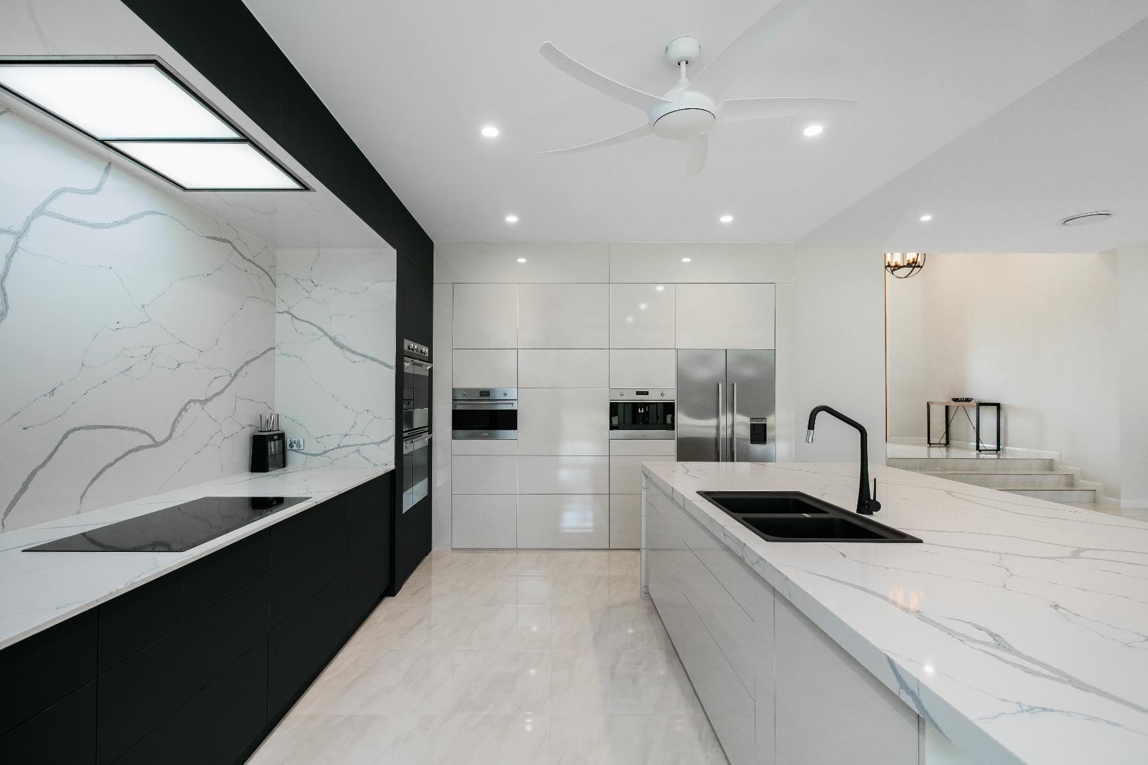 A Kitchen With Black and White Cabinets and a Ceiling Fan — Ashlee Jones Homes in Gordonvale, QLD